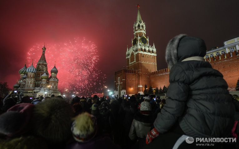 Москвичи и гости столицы смотрят праздничный фейерверк на Красной Площади